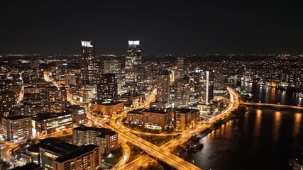 Spectacular aerial view of a sprawling urban metropolis at night, with glowing skyscrapers and a dazzling network of illuminated highway interchanges - Powered by Adobe