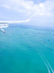 Boats dotting a vast turquoise ocean under a cloudy sky