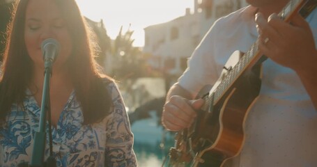 Close up of singer and guitarist performing near poolside at resort