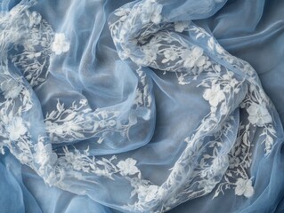 Delicate blue tulle fabric adorned with intricate white floral embroidery adding a touch of ethereal elegance to any design