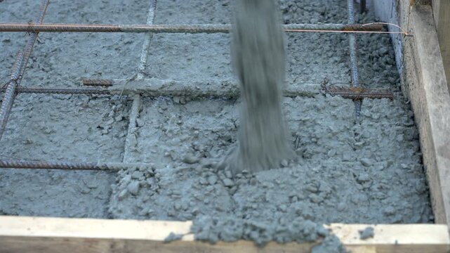 Concrete being poured onto rebar foundation at construction site