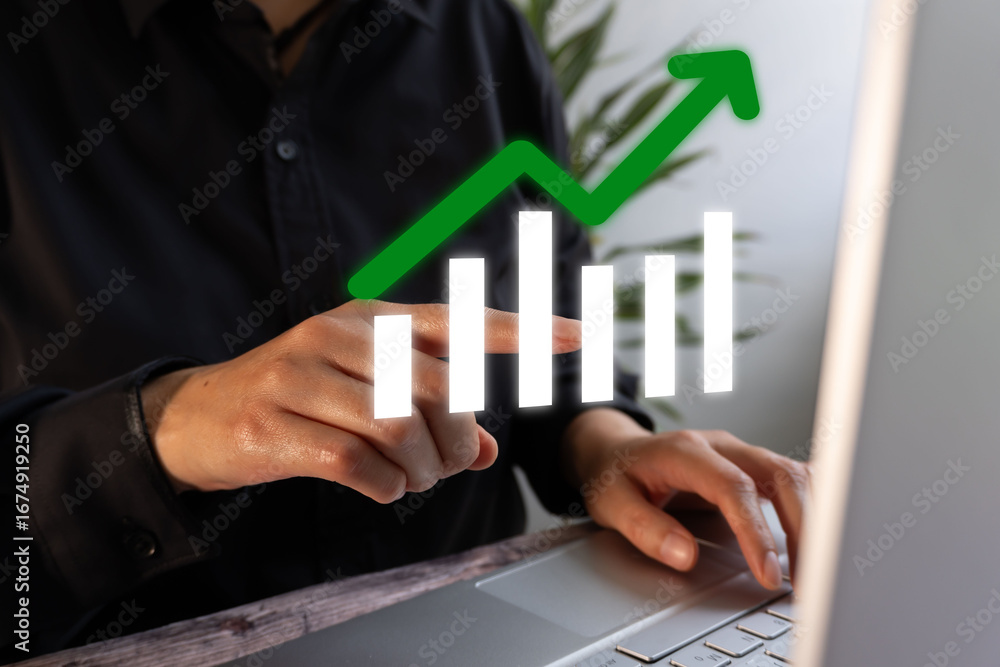 Poster person working on computer while pointing at a floating icon of a graph with an upward arrow