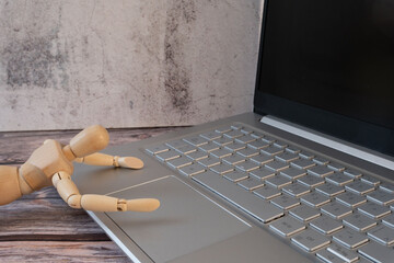 Wooden mannequin working on a large laptop