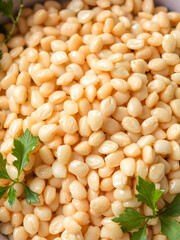 Grain Medley A closeup of barley tightly packed in a bowl showcasing its pearly grains and subtle shine surrounded by fresh herbs for a touch of color.