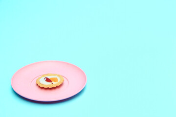 Mini fruit pies on pink plate topped with fruit slices, blue  background