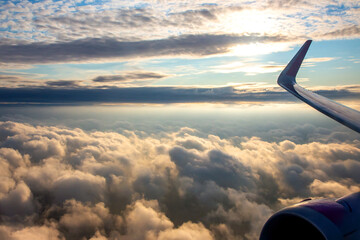 Captivating view of clouds and sunlight from an airplane wing in the sky at sunrise