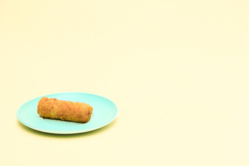 Rissole or risoles on a blue plate with a yellow background
