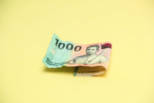 A crisp Indonesian one thousand rupiah banknote placed against a bright yellow background, highlighting its intricate design and cultural symbolism - Powered by Adobe