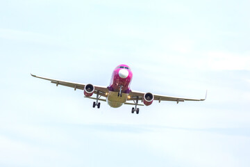 Airplane approaches landing at a busy airport under cloudy skies during daytime