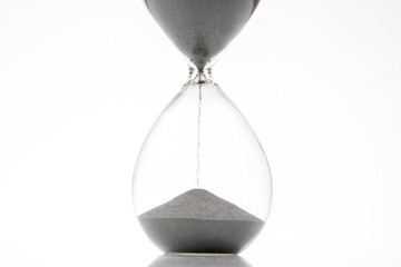 Elegant hourglass displaying flowing black sand against a white background