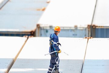 A port employee, stevedore, standing on deck of a container ship during his daily routine...