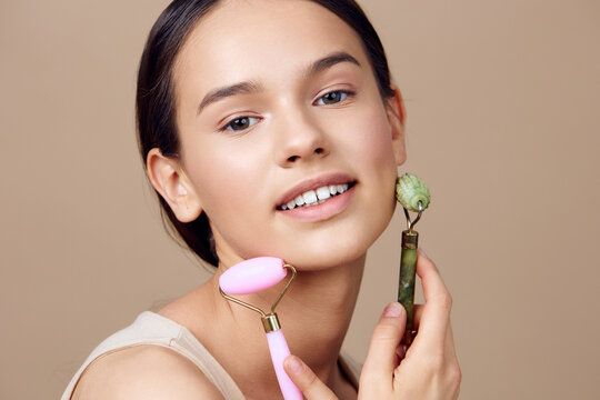 Young woman with a glowing complexion using facial rollers for skincare, showcasing beauty and self care in a minimalistic setting
