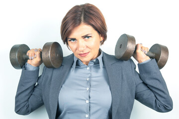 Strong businesswoman lifting weights indoors in a professional outfit