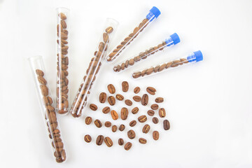 Coffee beans arranged in test tubes and scattered on a white surface