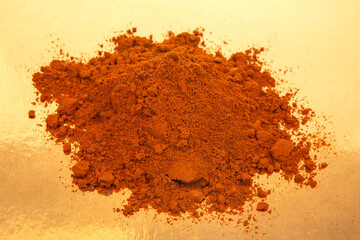 Rich red brown spice powder piled on a reflective surface for culinary use