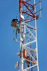 communication tower with antennas and security cameras, technician climbing for repairs and...