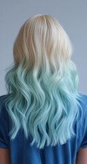 Naklejka premium Close-up of a woman from behind with shoulder-length blonde hair, half dyed in ombre green to white and the other half in long pastel blue waves