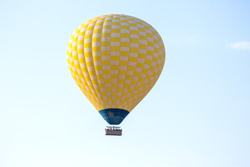 Colorful hot air balloon flying above a scenic landscape in clear blue sky