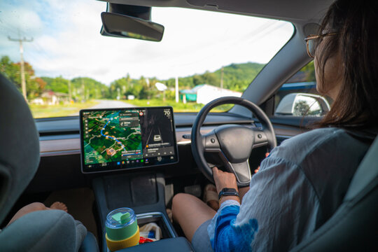 Woman drive modern EV car with GPS navigator travel in nature village