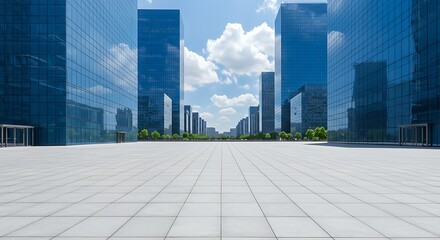 Fototapeta premium Empty paved plaza between modern glass office buildings under a partly cloudy sky.