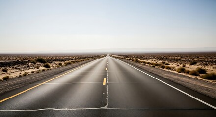 Desert highway disappearing into the distance under a bright blue sky