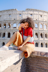 A cheerful child poses confidently with bright enthusiasm before the Colosseum in Rome, capturing a joyful moment in a historic setting that reflects their happiness in the bustling city