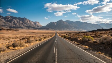 Long empty desert highway stretching towards distant mountains under a cloudy sky