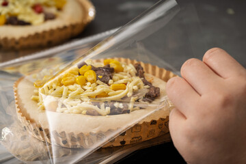 A Delicious Beef and Corn Pizza Being Packaged for Freshness and Convenience