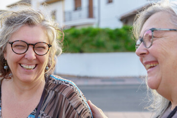 Two cheerful senior women enjoying each other's company outdoors, sharing laughter and happiness