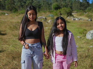 Sisters walking together in nature holding hands