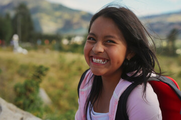 Smiling student girl with backpack enjoying mountain scenery