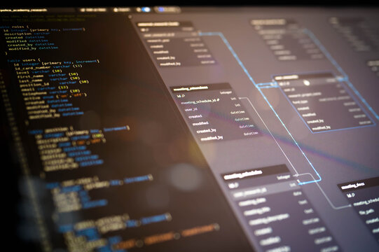 Blurred close-up of SQL database structure with source code and ER diagram on screen, showcasing back-end data architecture for software engineering and enterprise-level applications.