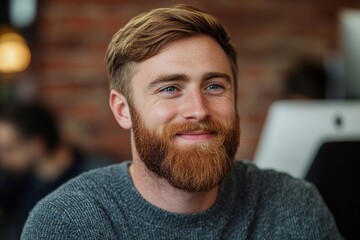 Close-up photo of smiling young man with a beard sitting in the office at the workplace, looking at the laptop screen while working efficiently, Generative AI