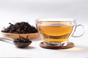 Black tea in cup glass with dried tea leaves on white background, Healthy herbal hot drink