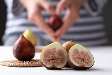 Fresh fig on white table with hand holding fig (heart shape) background, Autumn fruit