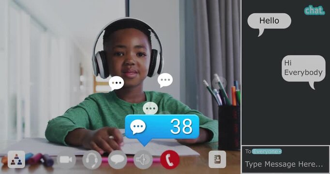 Schoolboy writing notes while tracking animated chat badges rising after Hello during online class