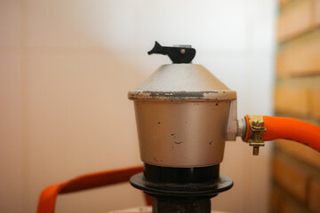 Close-up of a household butane gas regulator connected to an orange hose
