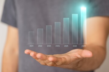 A hand displays a projected bar graph illustrating positive growth trends from 2021 to 2025, highlighting increasing progress over time.