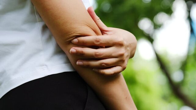 Woman has pain in his elbow and tendon muscles and he relieves the pain with a massage. Health and healing concept	
