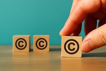 Light-toned wooden blocks, each bearing a  symbol, are arranged on a light-colored surface, with a hand positioning one block, against a teal-colored backdrop.