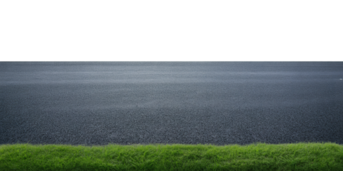 Asphalt road and vibrant green grass against a dark sky, perfect for transportation and nature themes