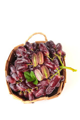 Fresh Red Grapes in Wicker Basket with Mint Leaf Garnish on White Background