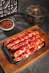 Air-dried Chinese Sausages on Wooden Board with Tea and Peppercorns Traditional Asian Food Preparation