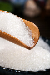 White cane sugar crystals in wooden spoon on table fine granulated sweetener ingredient cooking baking macro closeup