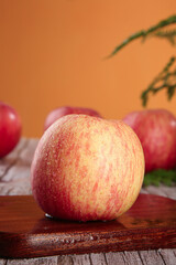 Fresh Red Striped Fuji Apples on Wooden Table with Warm Orange Background