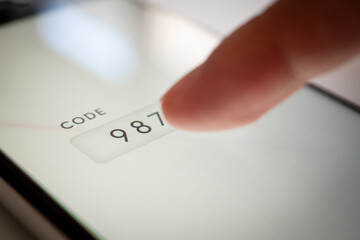 スマホに認証コードを指で入力する写真 (ログイン、ロック解除、二段階認証)