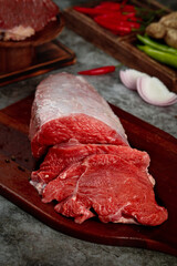 Fresh Cut Raw Beef Slices on Wooden Board with Vegetables for Meal Preparation