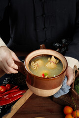 Traditional Clay Pot Lamb Soup with Fresh Vegetables and Chili Peppers on Wooden Table