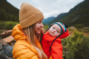 Mom with infant baby traveling in mountains family travel mother and child walking together...