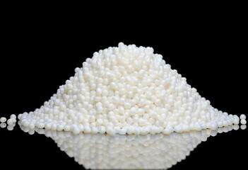 A mound of white polypropylene pellets sits on a reflective surface against a black backdrop,  pile,  white